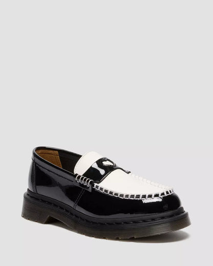 Black and white patent leather loafer on a light gray background