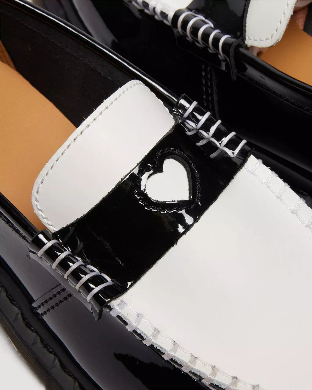Close-up of a black and white shoe with a heart design on the tongue.