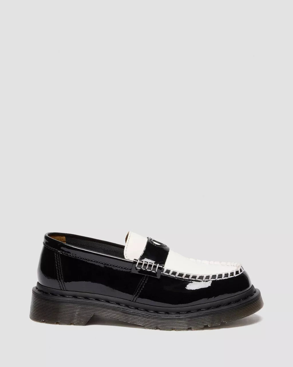 Black patent leather loafer with a silver buckle on a light gray background