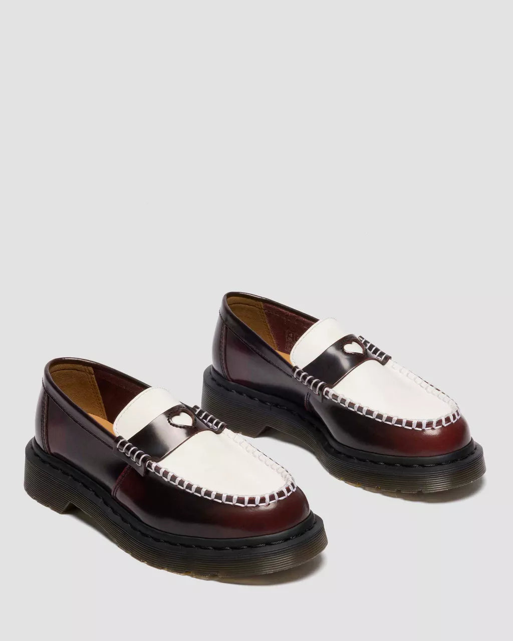 Pair of brown and white loafers on a light gray background