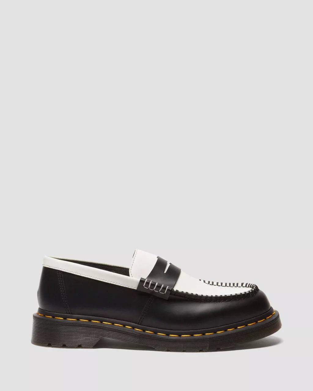 A pair of two-tone smooth leather loafers with a contrast of black and white colors and a distinct stitching detail on the sole.