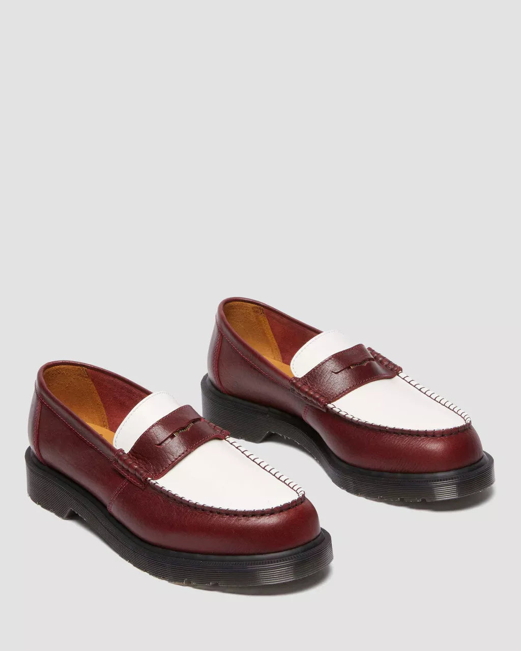 Pair of maroon and white loafers on a gray background