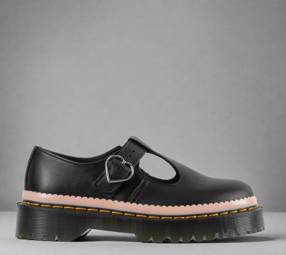 A black sandal with a heart-shaped buckle on the strap and a thick, chunky sole featuring yellow stitching.