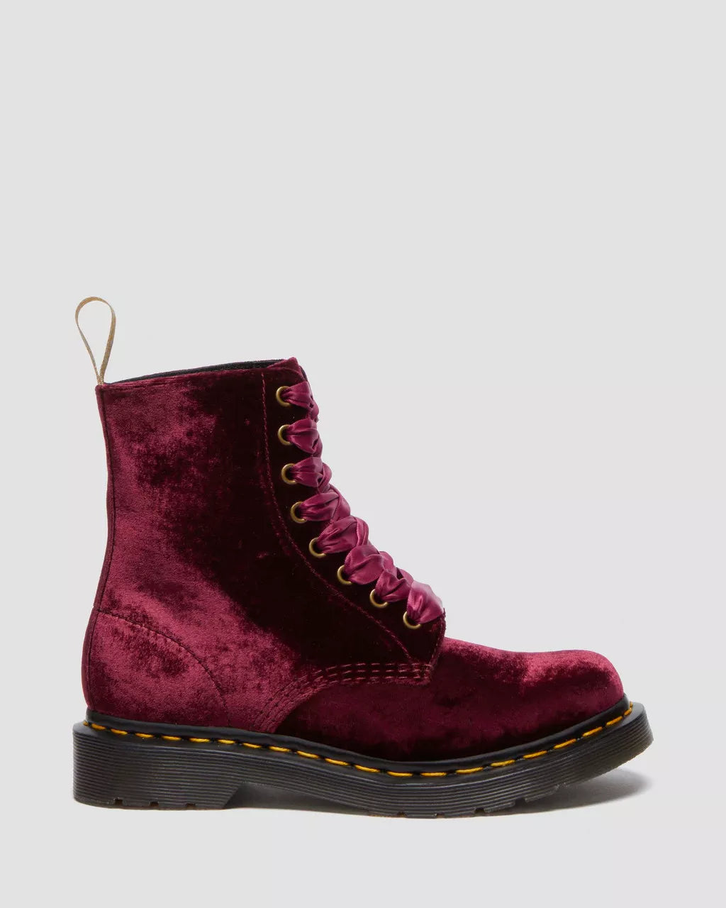 A pair of red velvet lace-up boots with gold eyelets and tonal ribbon laces, featuring a classic 8-eye design and the brand's signature on the heel loop.