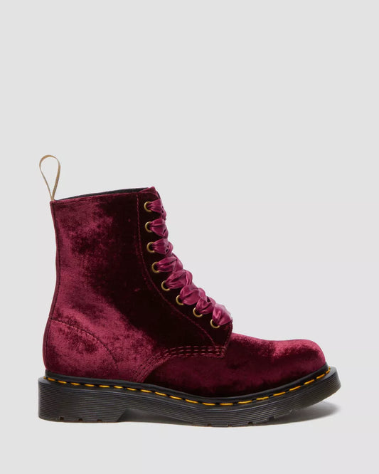 A pair of red velvet lace-up boots with gold eyelets and tonal ribbon laces, featuring a classic 8-eye design and the brand's signature on the heel loop.