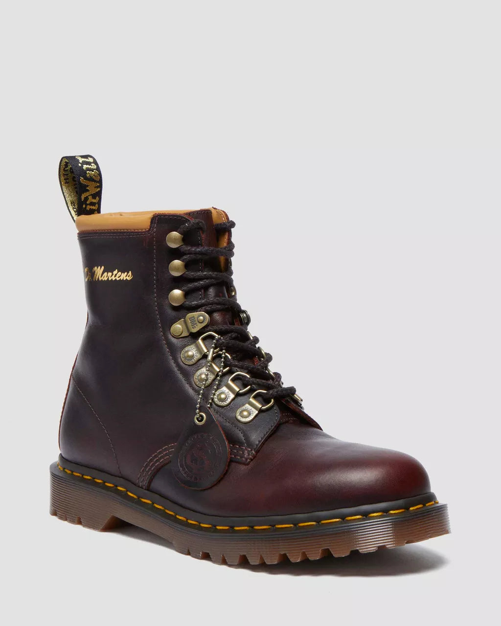 Brown leather boot with gold laces and stitching on a light gray background