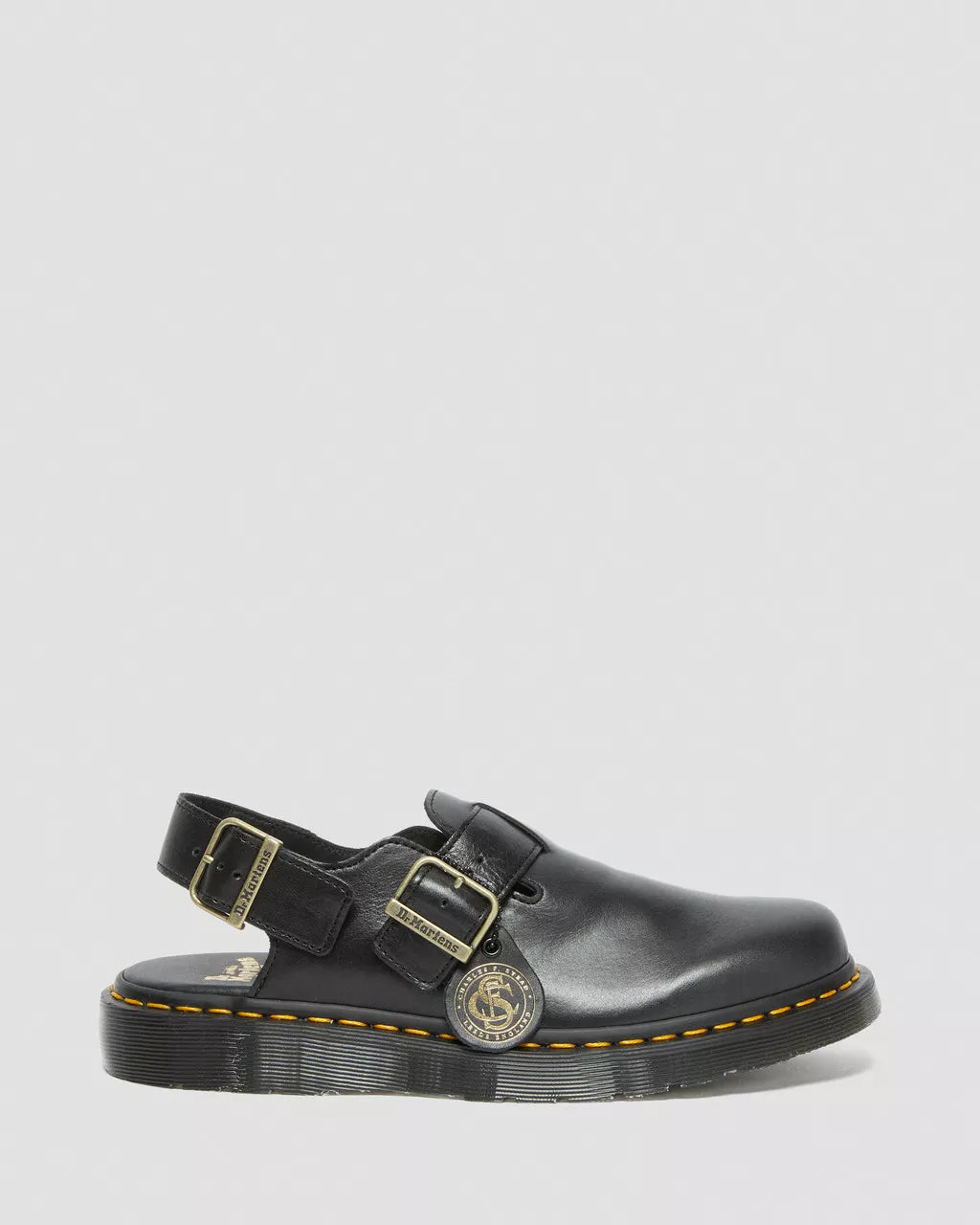 Black leather sandal with gold buckles on a light gray background