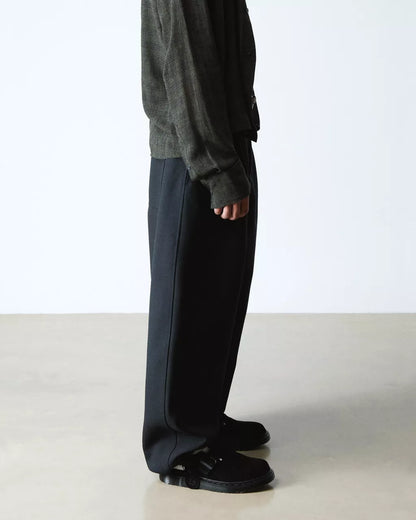 Person wearing dark gray pants and a matching sweater on a white background