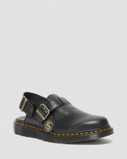 Black leather shoe with gold buckle on a light gray background