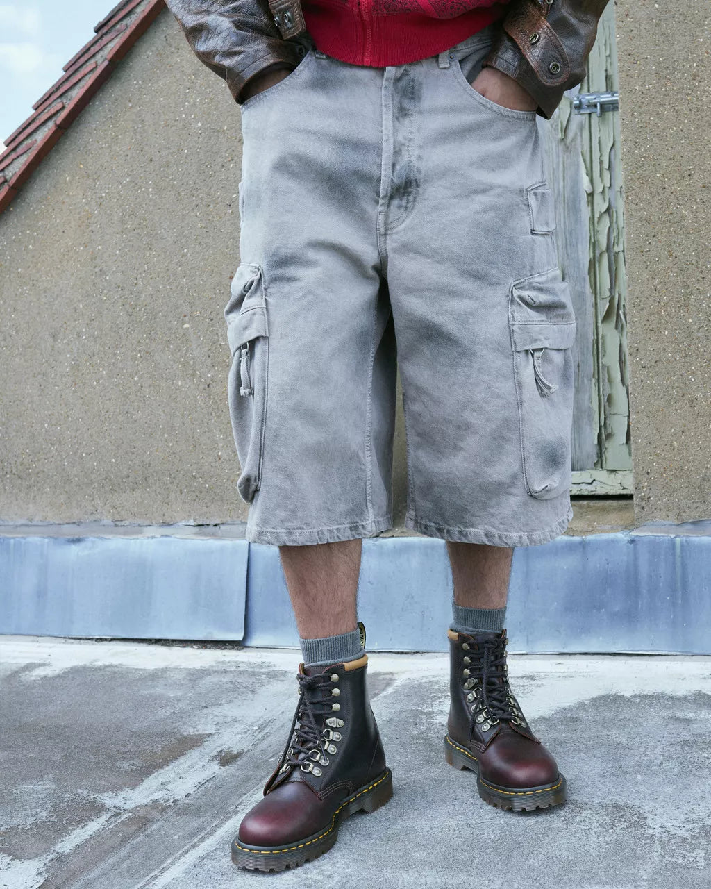Person wearing gray cargo shorts and brown boots standing on a rooftop.