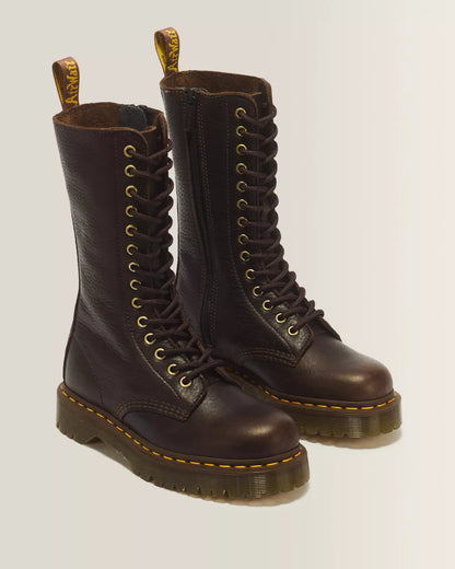 A pair of dark brown leather lace-up boots with gold-tone eyelets, yellow stitching along the sole, and pull tabs, photographed on a light gray background.