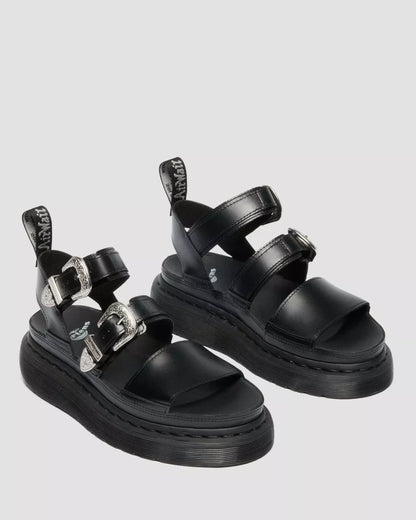 Black sandals with multiple straps on a light gray background