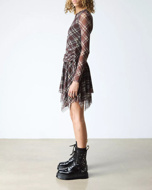 Person wearing a plaid dress and black boots on a plain background