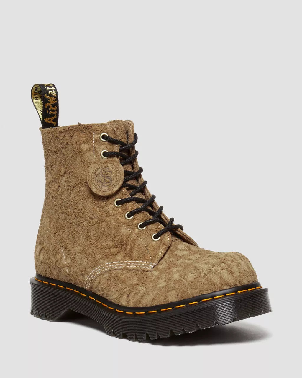Brown suede boot with black sole on a light gray background