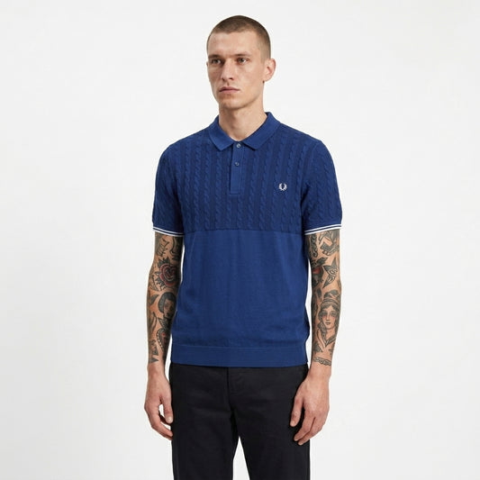 Man wearing a blue polo shirt with a brand logo on a white background
