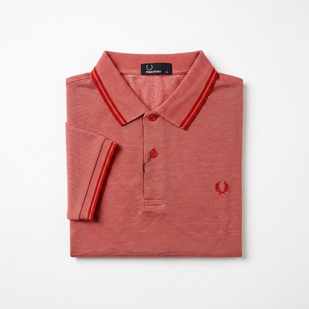 Twin-tipped Fred Perry folded red polo shirt with white collar and trim on a light gray background