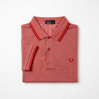 Twin-tipped Fred Perry folded red polo shirt with white collar and trim on a light gray background
