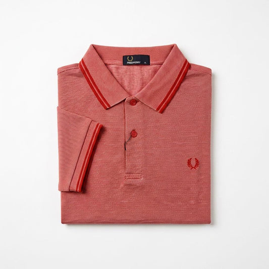 Twin-tipped Fred Perry folded red polo shirt with white collar and trim on a light gray background