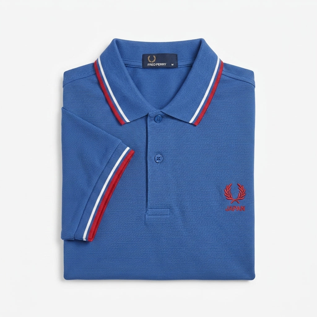 Fred Perry vintage world cup Japan twin-tipped blue polo shirt with red and white accents on a light gray background