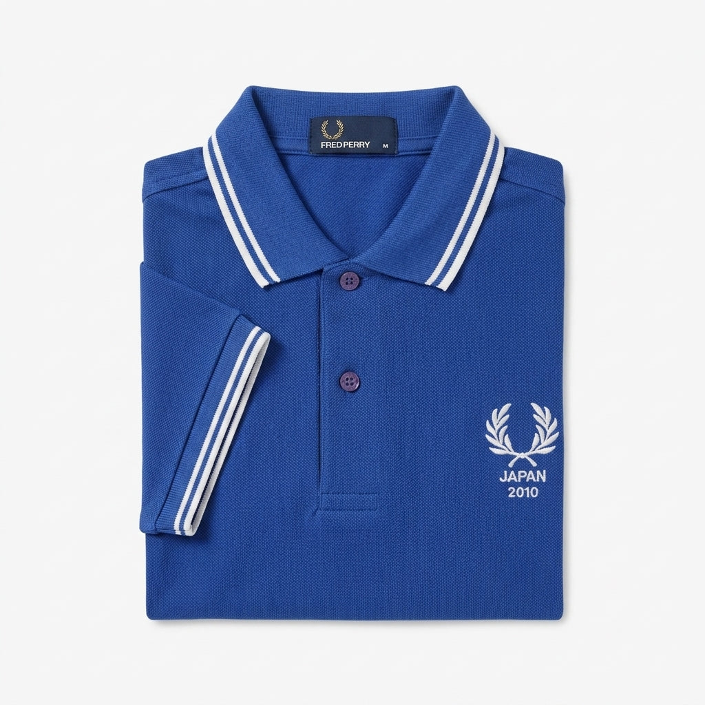 Fred Perry vintage world cup Japan 2010 twin-tipped blue polo shirt with white accents and a brand logo on a light gray background