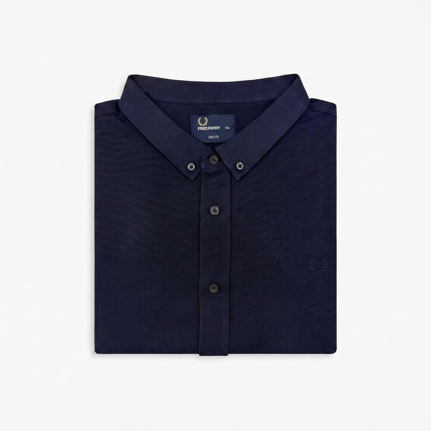 A folded navy blue button-down shirt by Fred Perry, shown on a clean white background. The shirt features a classic collar, button-down front, and the signature embroidered laurel wreath logo on the chest.