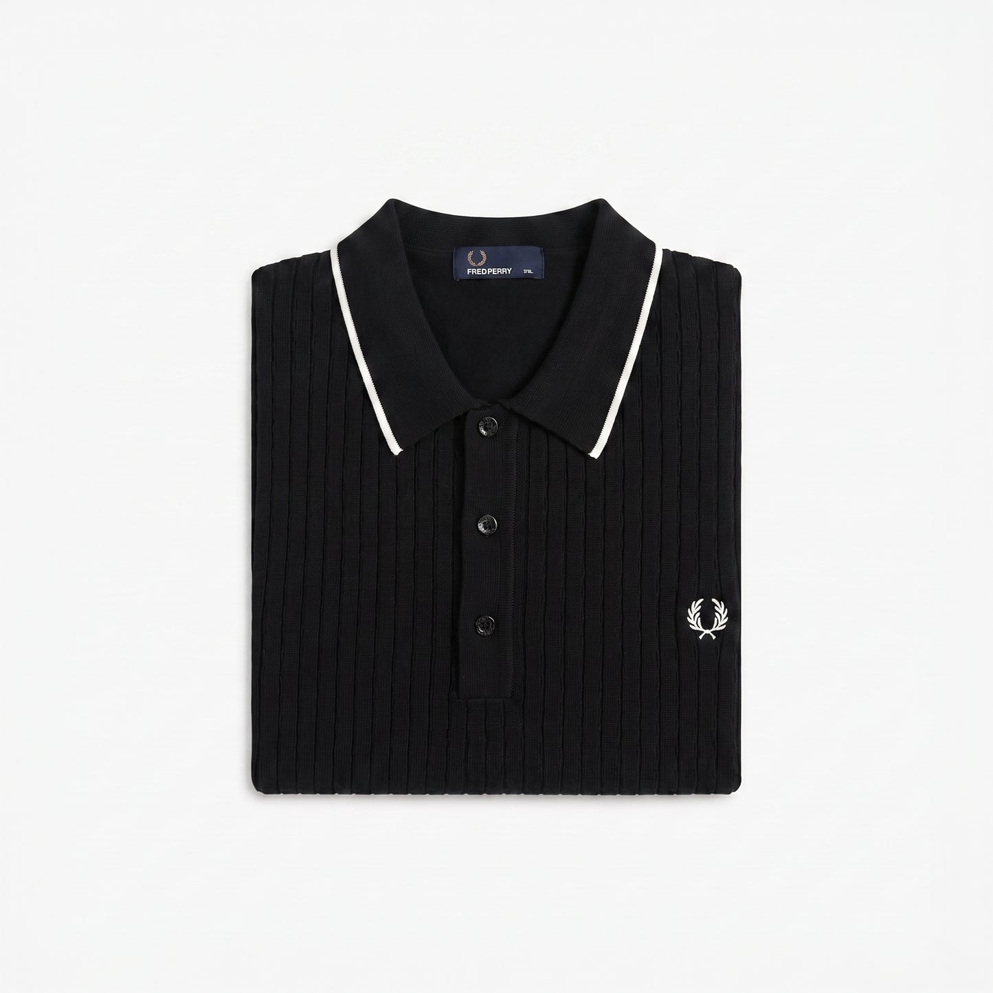 A folded black ribbed knit polo shirt by Fred Perry, featuring white piping along the collar and a small embroidered white logo on the chest, set against a plain white background.
