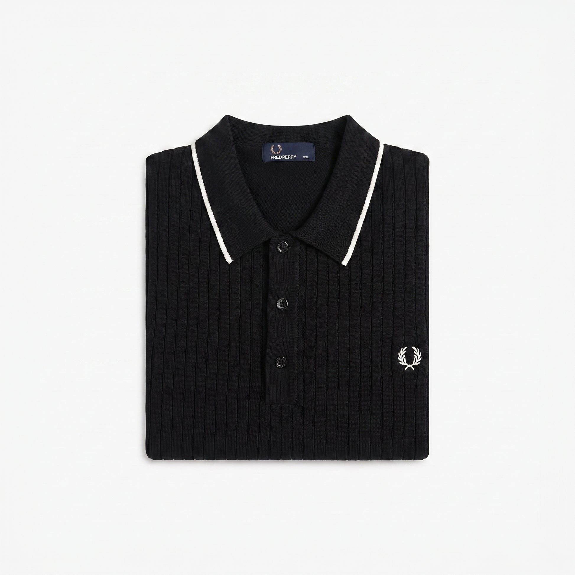 A folded black ribbed knit polo shirt by Fred Perry, featuring white piping along the collar and a small embroidered white logo on the chest, set against a plain white background.