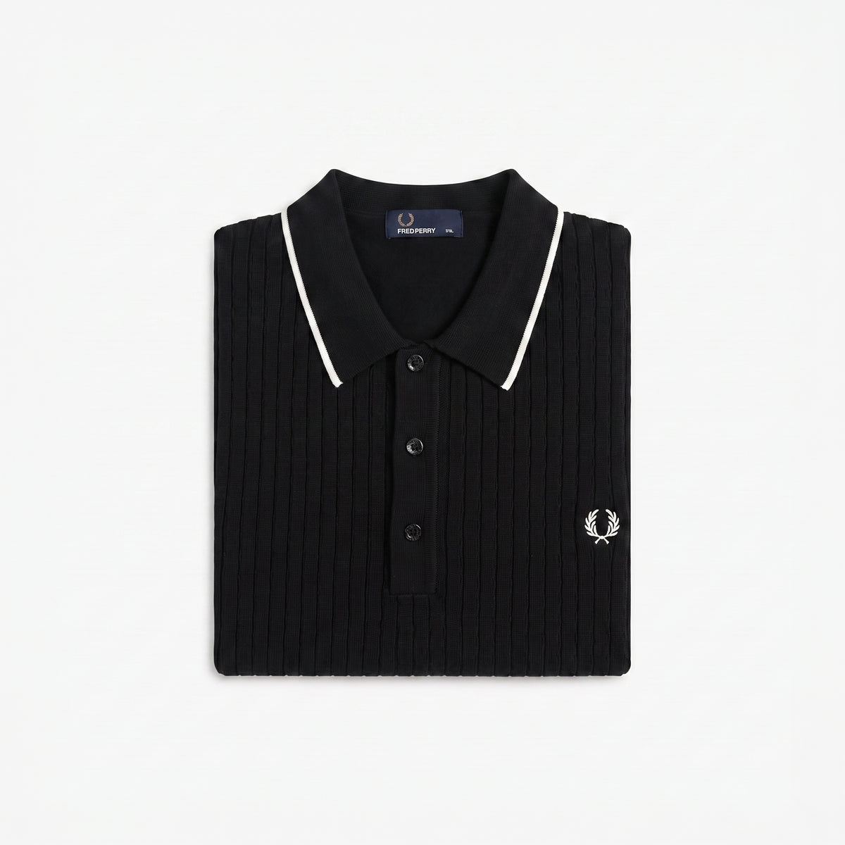 A folded black ribbed knit polo shirt by Fred Perry, featuring white piping along the collar and a small embroidered white logo on the chest, set against a plain white background.