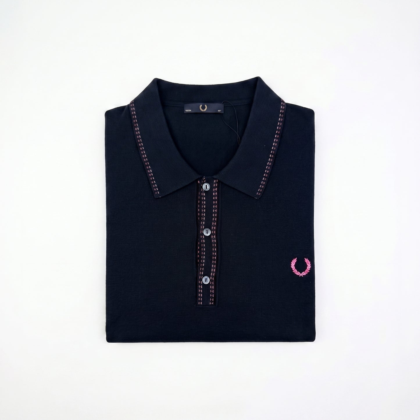 A folded dark navy polo shirt with pink contrast stitching and a pink embroidered laurel wreath logo on the left chest, displayed on a clean white background.