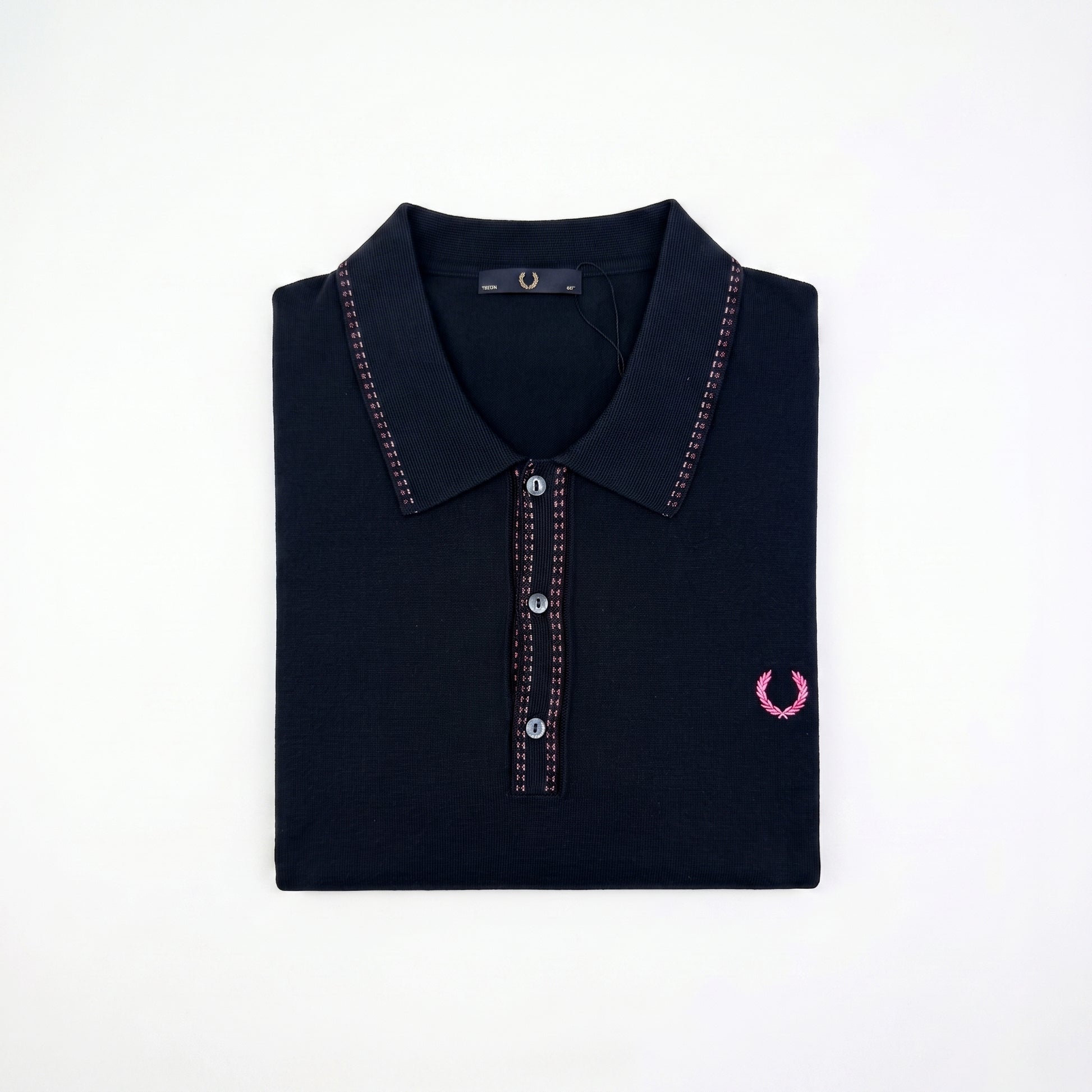 A folded dark navy polo shirt with pink contrast stitching and a pink embroidered laurel wreath logo on the left chest, displayed on a clean white background.
