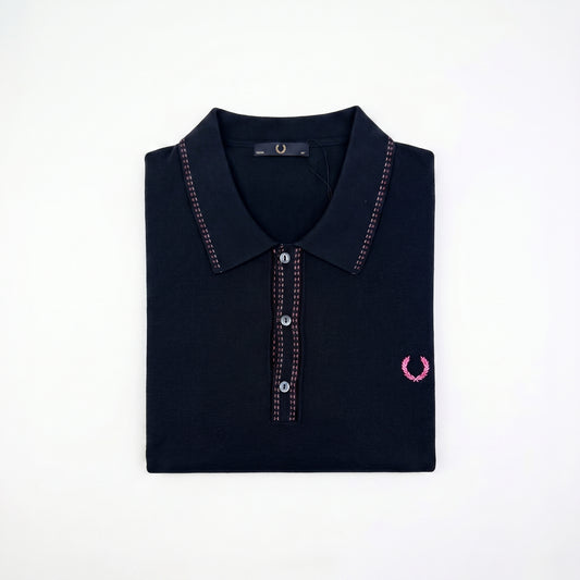 A folded dark navy polo shirt with pink contrast stitching and a pink embroidered laurel wreath logo on the left chest, displayed on a clean white background.
