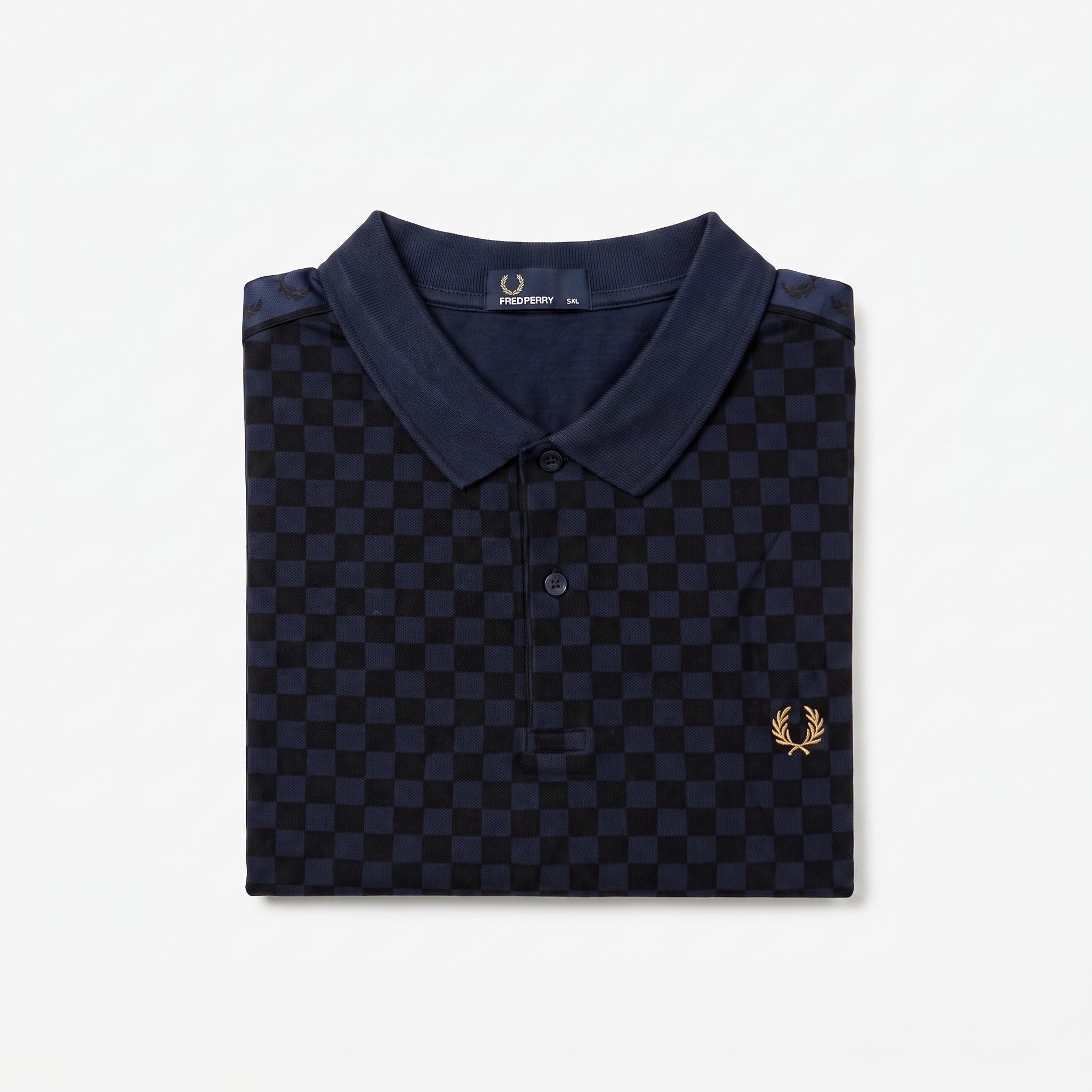 A folded navy blue polo shirt with a dark blue and black checkerboard pattern, featuring a small gold embroidered laurel wreath logo on the left chest. The brand label inside the collar reads ‘Fred Perry’