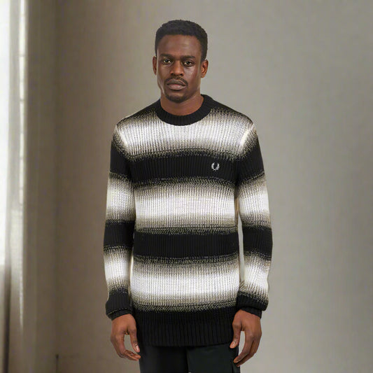 A male model wearing a Fred Perry black and white cable knit jumper.