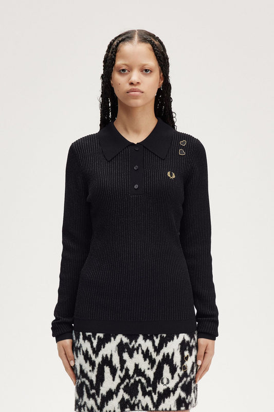 A woman wearing a black metallic ribbed knit top with three button placket and embroidered heart patches above the Laurel Wreath on a white background.