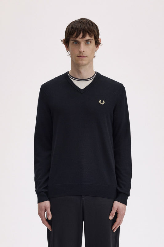 Person wearing a black Fred Perry sweater on a white background