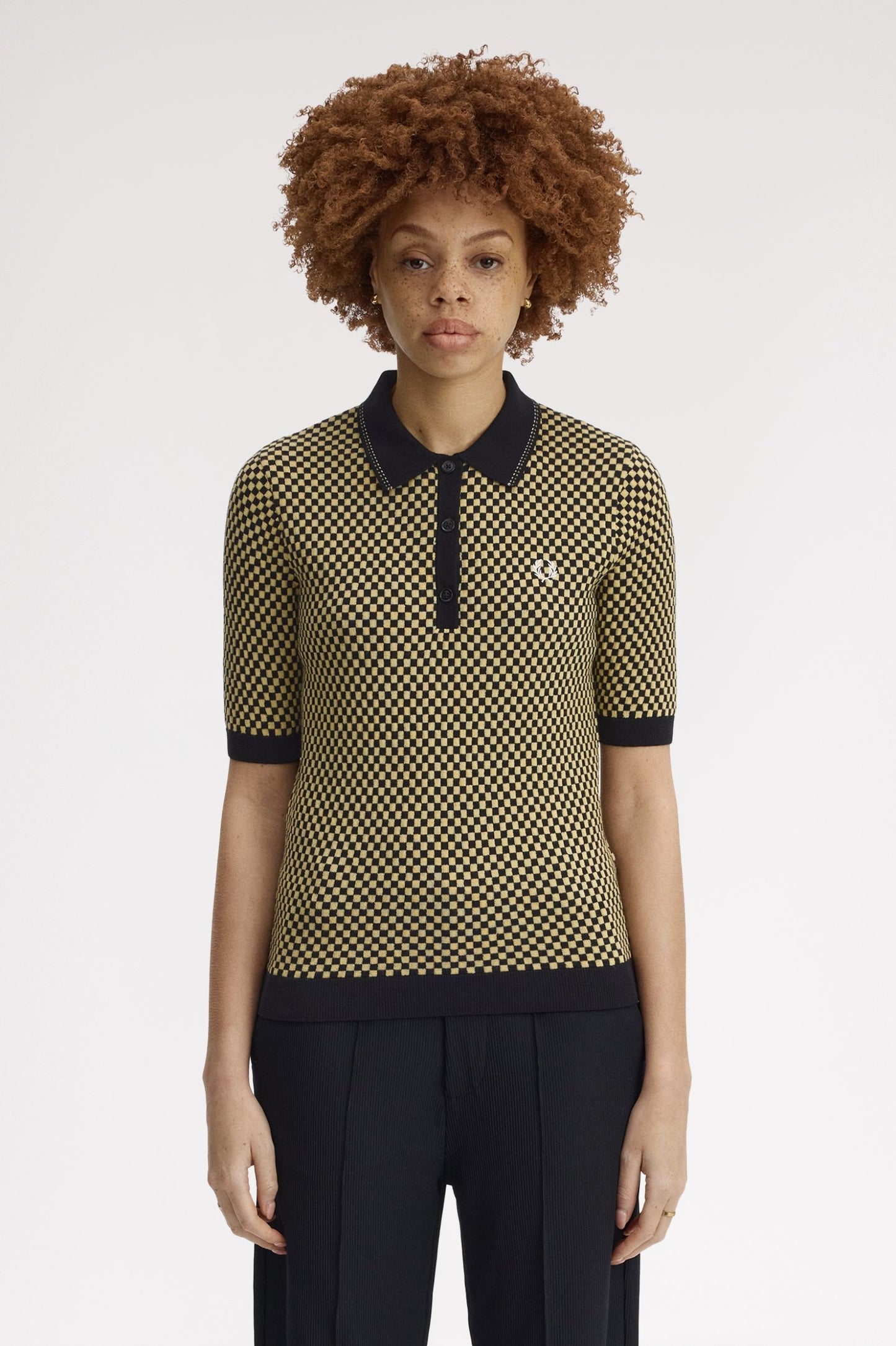Person wearing a patterned shirt with black collar and trim on a white background