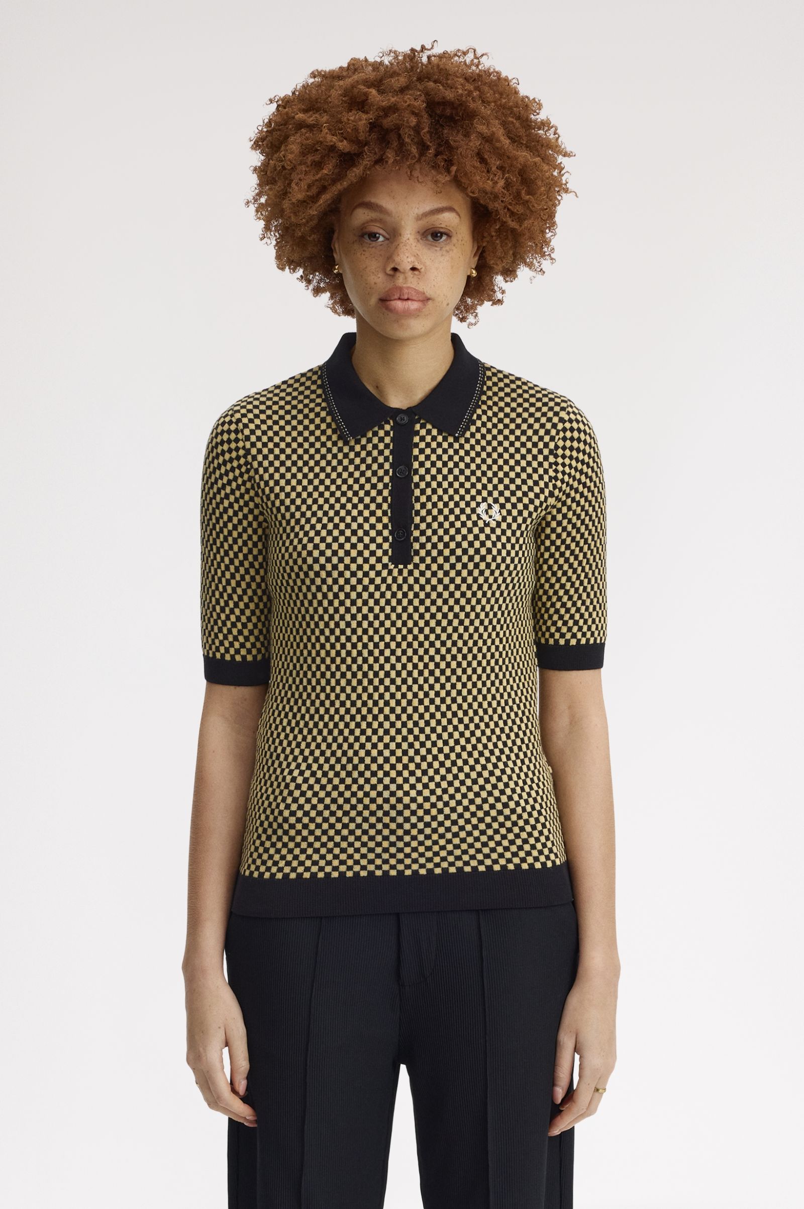 Person wearing a patterned shirt with black collar and trim on a white background