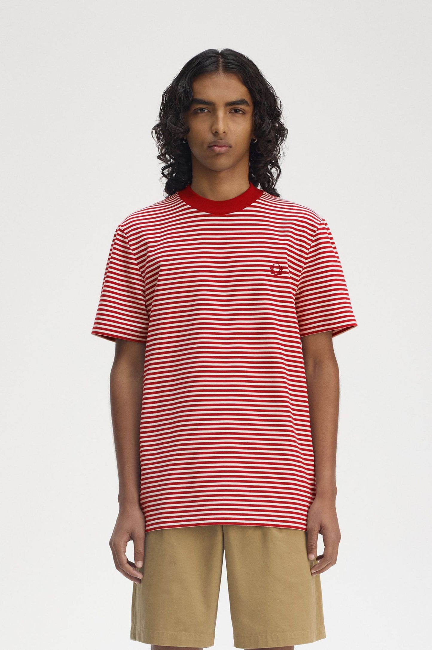 A man wearing a slim fit, black and white striped t-shirt with the Laurel Wreath logo on the left chest.