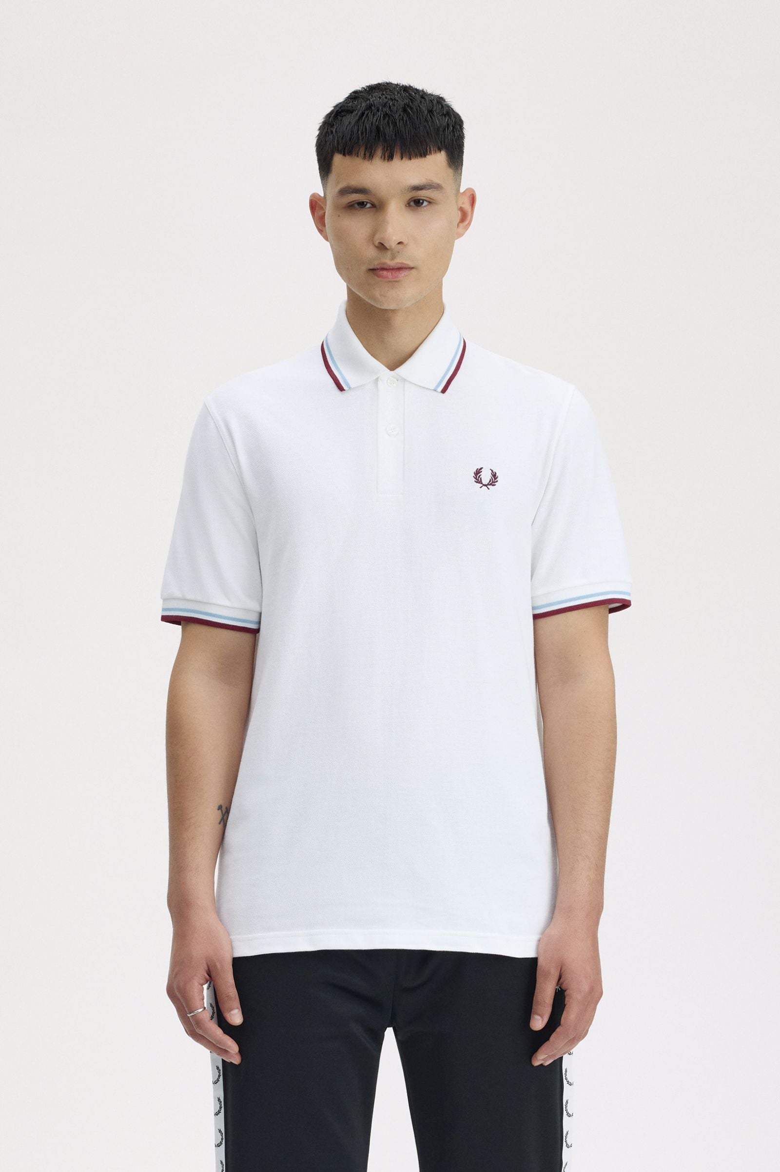 Person wearing a white polo shirt with red and blue accents on a plain background