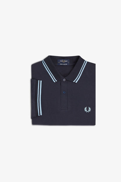 Folded navy polo shirt with white trim on a light gray background