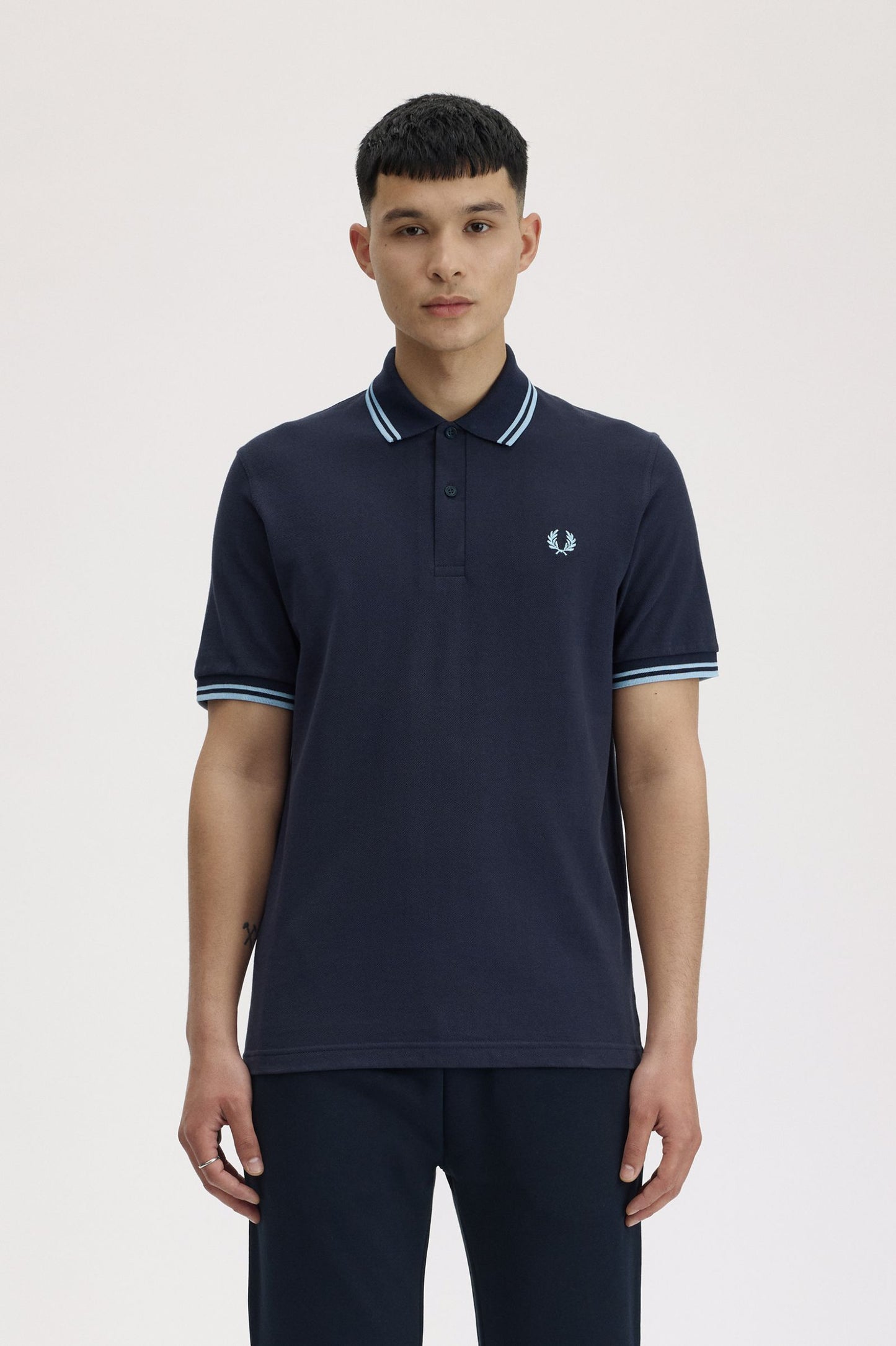 Person wearing a navy polo shirt with a brand logo on a light background