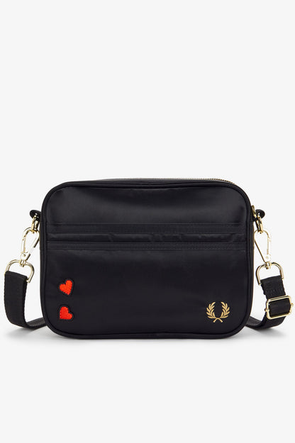 Black handbag with heart designs and a brand logo on a white background