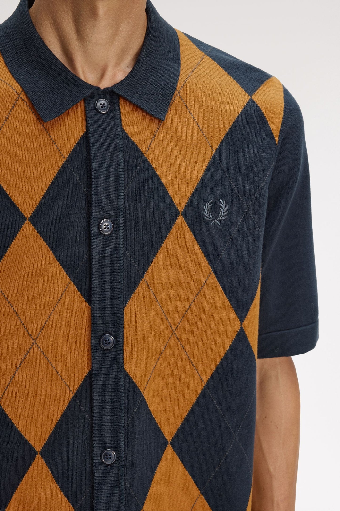 Navy and orange argyle patterned shirt with brand logo on a white background