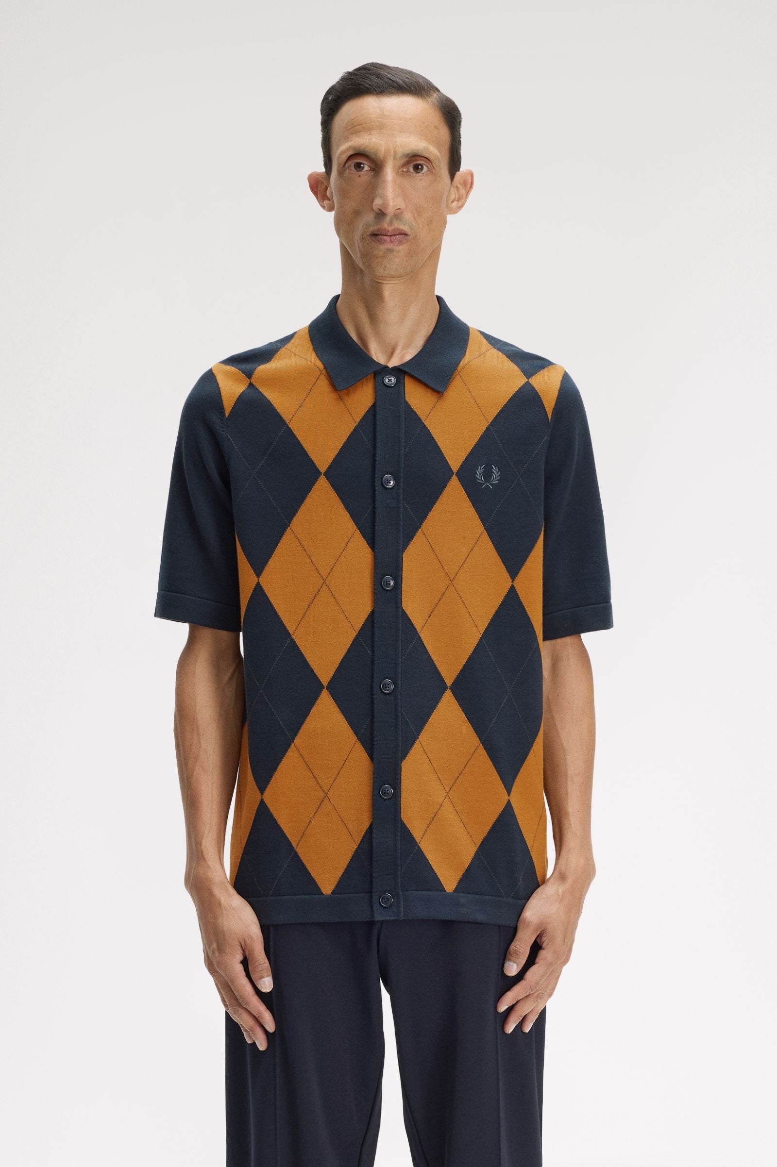 Man wearing a black and orange argyle shirt on a white background