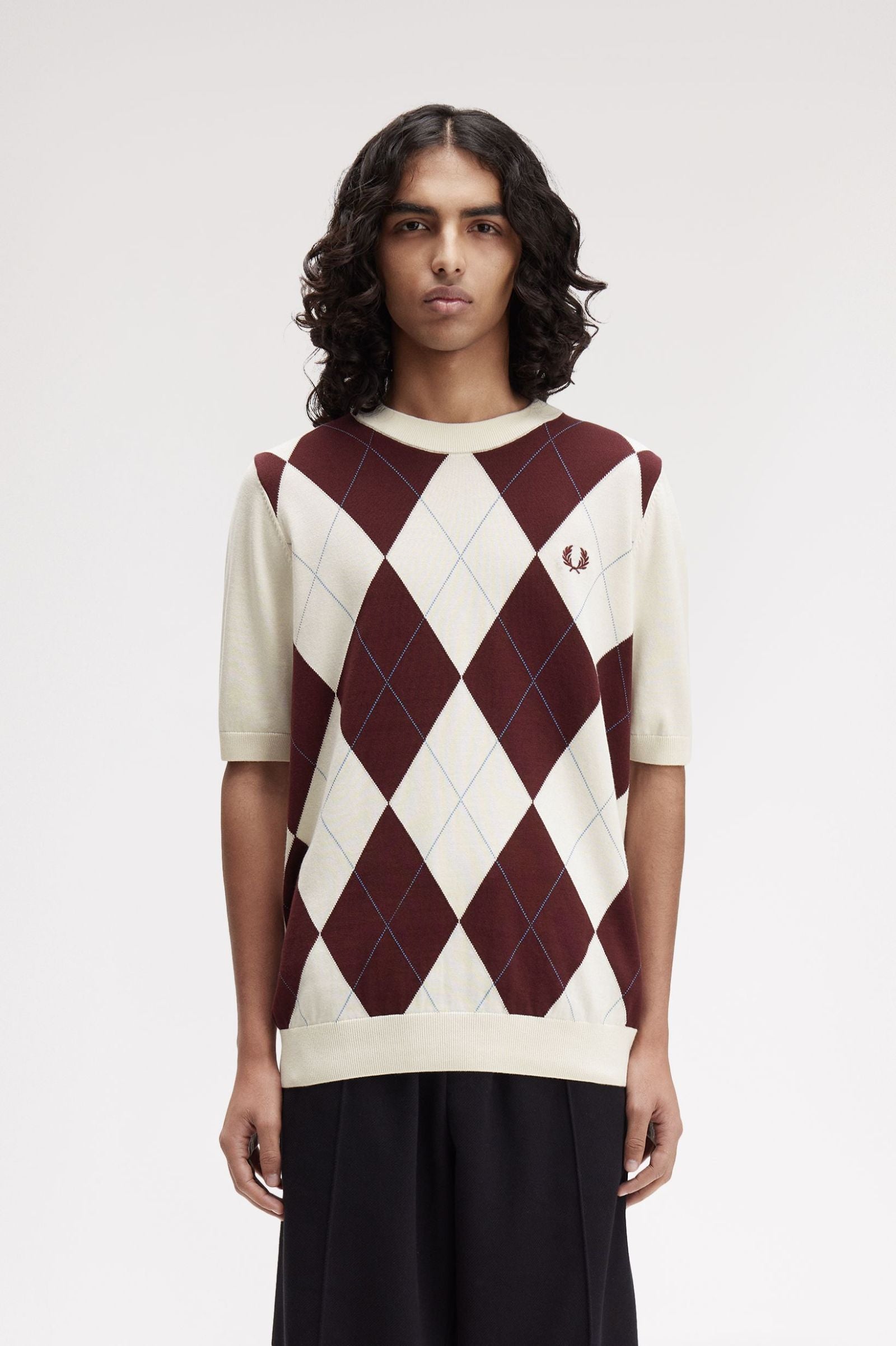 Person wearing a maroon and white argyle sweater on a plain background