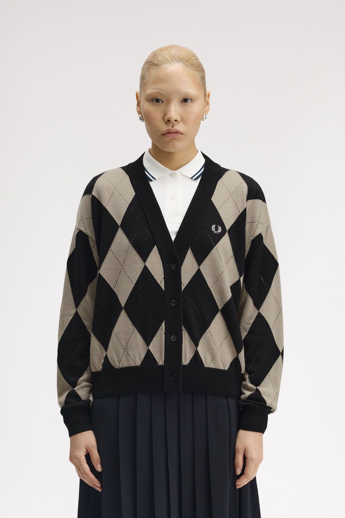 Person wearing a black and beige argyle patterned cardigan on a white background