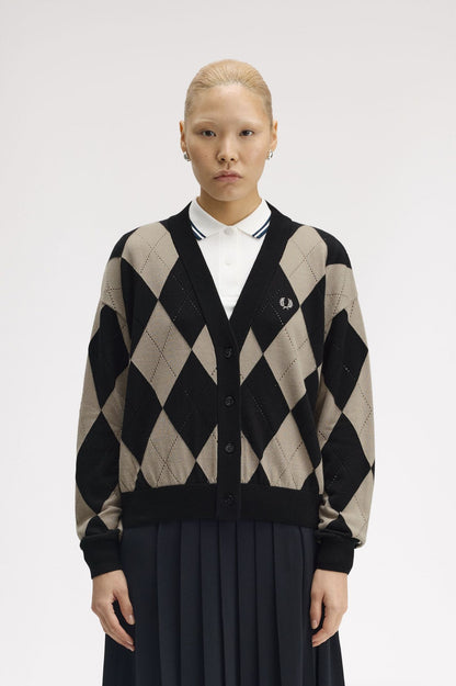 Person wearing a black and beige argyle patterned cardigan on a white background