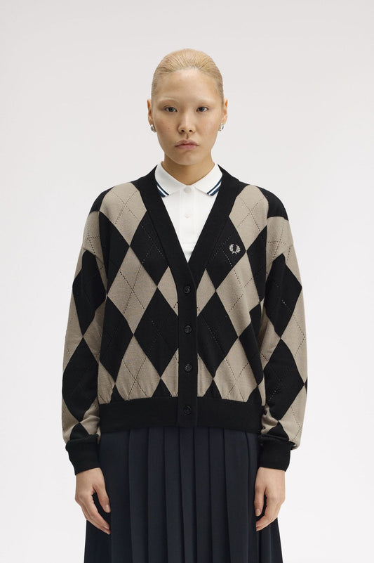 Person wearing a black and beige argyle patterned cardigan on a white background