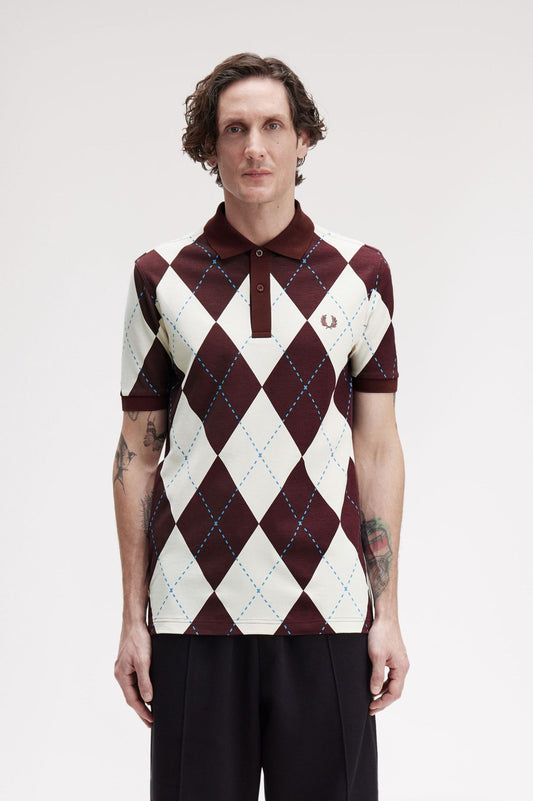 Person wearing a patterned polo shirt with a visible brand logo on a plain background