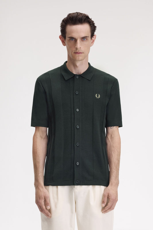 A male model wearing a night green Fred Perry button-through short-sleeve shirt.